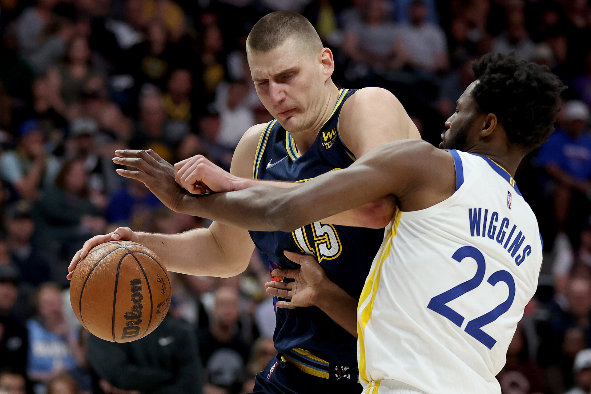 Denver Nuggets center Nikola Jokic, left, dribbles with his right hand while driving against Golden State Warriors forward Andrew Wiggins on Sunday, April 24, 2022, in Denver.