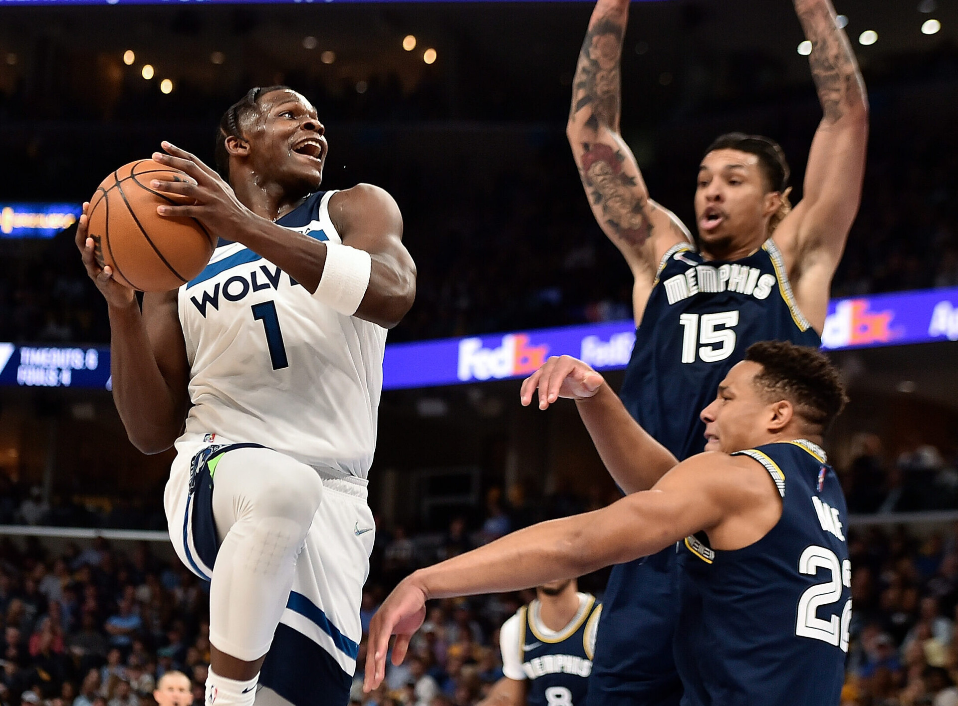 Minnesota Timberwolves forward Anthony Edwards, left, leaps into the air with both hands on the ball on a drive against the Memphis Grizzlies' Brandon Clarke and Desmond Bane, right, on Tuesday, April 26, 2022, in Memphis, Tenn.