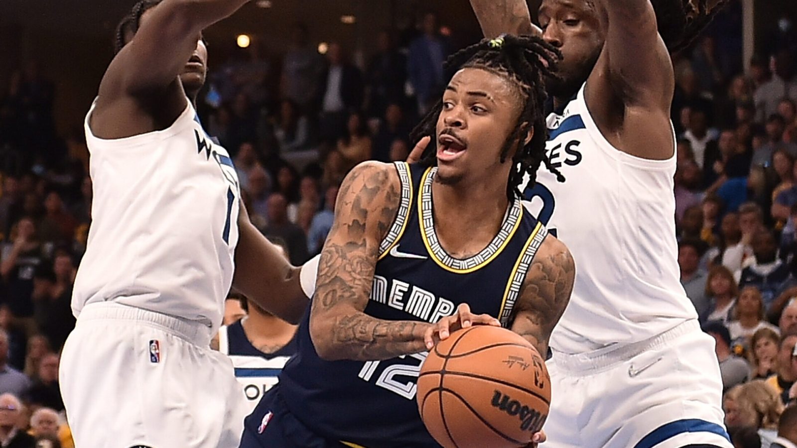 Memphis Grizzlies guard Ja Morant, center, looks to pass around the outstretched arms of the Minnesota Timberwolves' Anthony Edwards, left, and Taurean Prince, right, on Tuesday, April 26, 2022, in Memphis, Tenn.