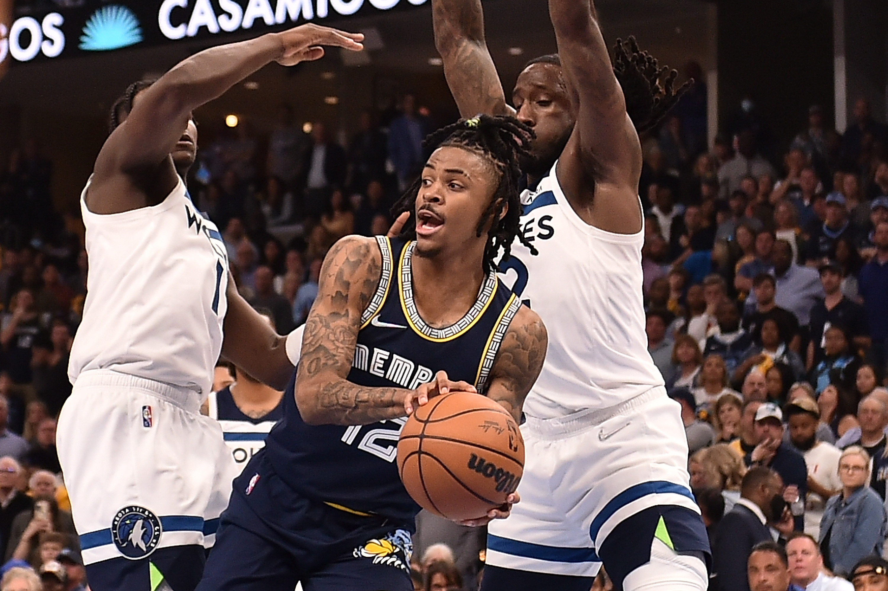 Memphis Grizzlies guard Ja Morant, center, looks to pass around the outstretched arms of the Minnesota Timberwolves' Anthony Edwards, left, and Taurean Prince, right, on Tuesday, April 26, 2022, in Memphis, Tenn.