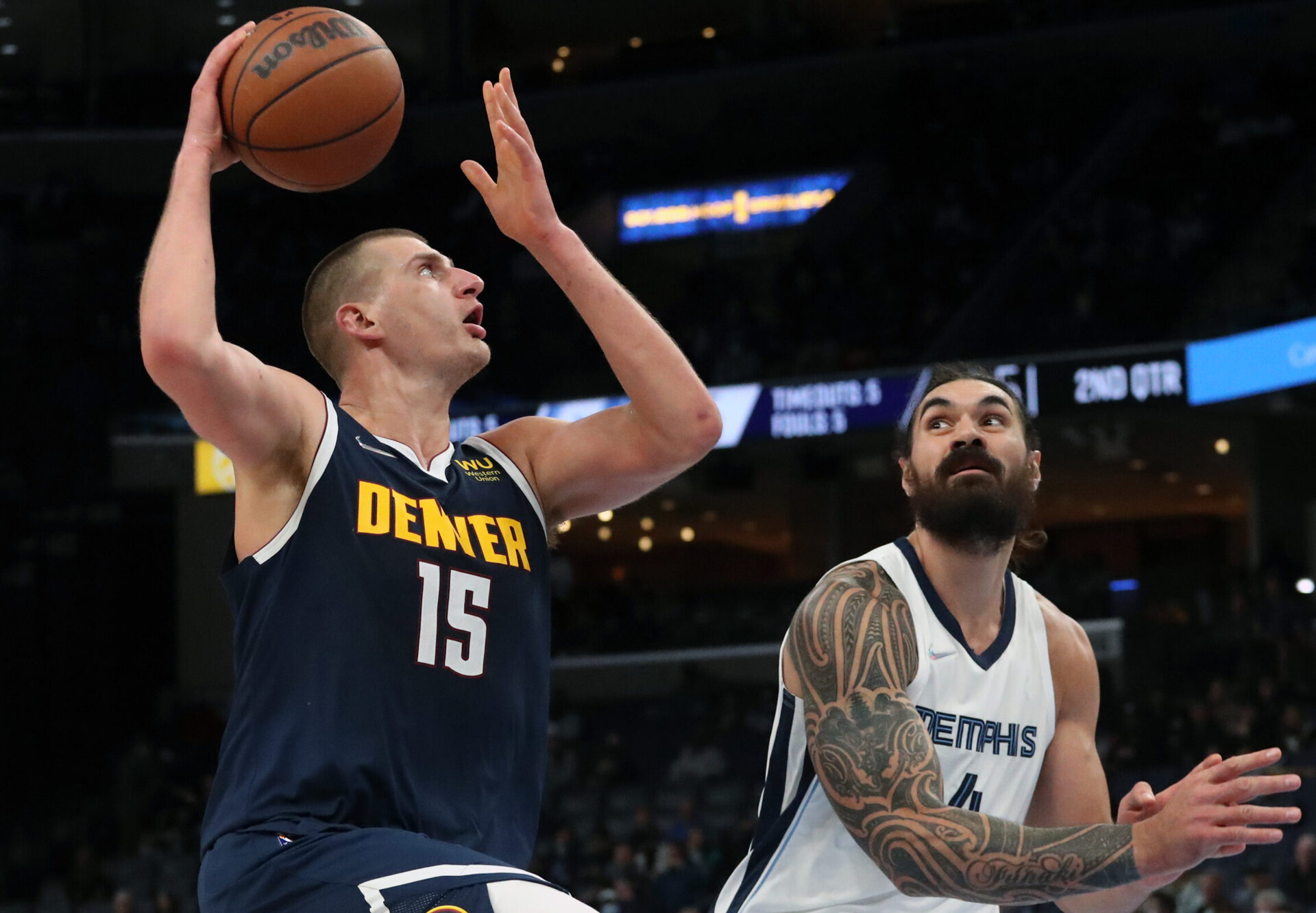 Denver Nuggets center Nikola Jokic (left) looks to shoot the basketball with his right hand as he drives to the basket while Memphis Grizzles center Steven Adams (right) defends