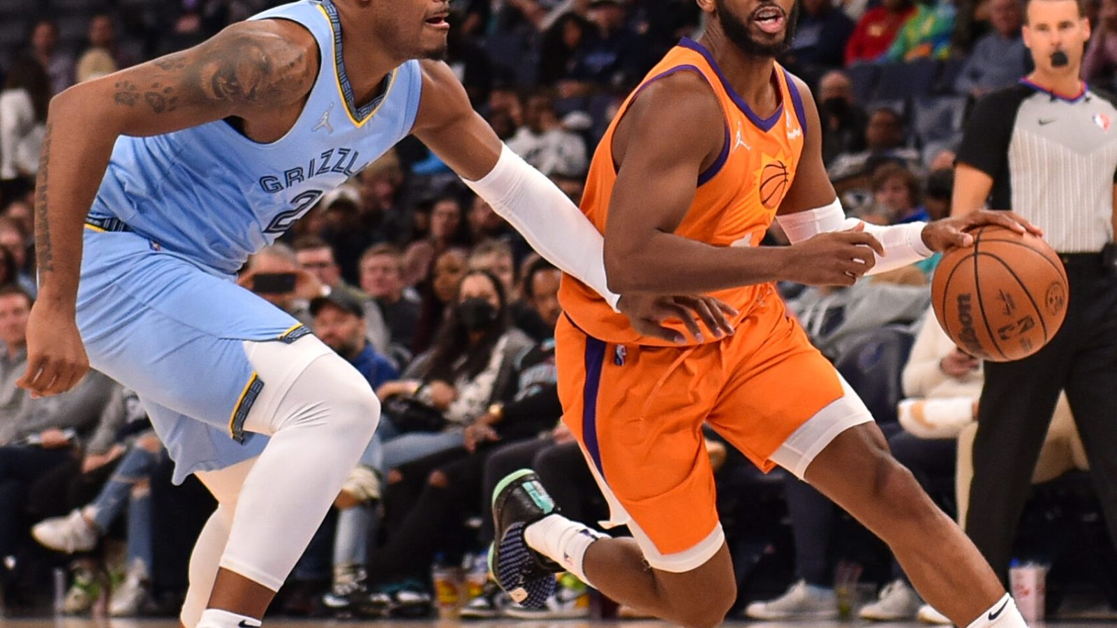 Phoenix Suns guard Chris Paul (right) dribbles the ball with his left hand and drives past Memphis Grizzlies center Xavier Tillman Sr. (left) on his way to the basket