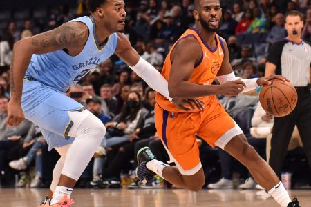 Phoenix Suns guard Chris Paul (right) dribbles the ball with his left hand and drives past Memphis Grizzlies center Xavier Tillman Sr. (left) on his way to the basket