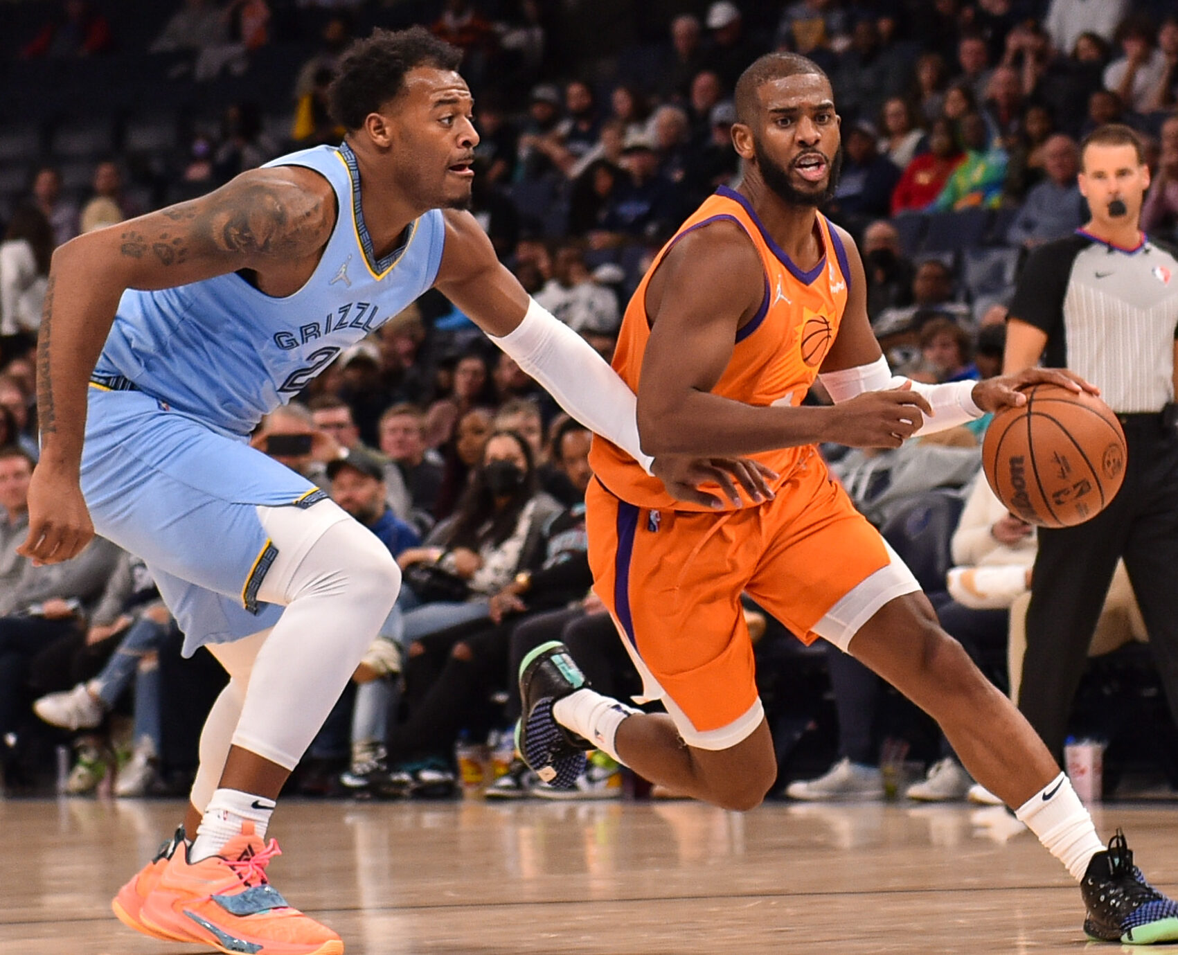 Phoenix Suns guard Chris Paul (right) dribbles the ball with his left hand and drives past Memphis Grizzlies center Xavier Tillman Sr. (left) on his way to the basket