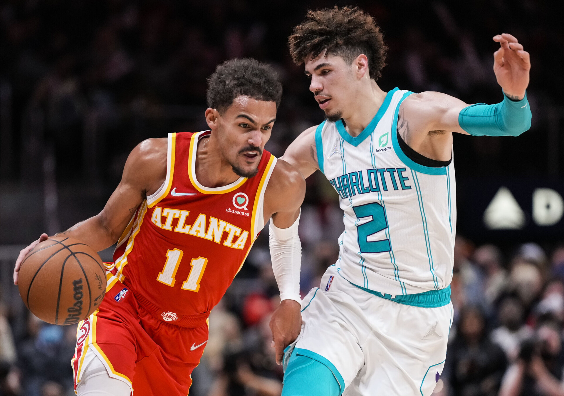 Atlanta Hawks guard Trae Young (left) dribbles the basketball with his right hand as he tries to work his away around the tight defense of Charlotte Hornets guard LaMelo Ball (right)