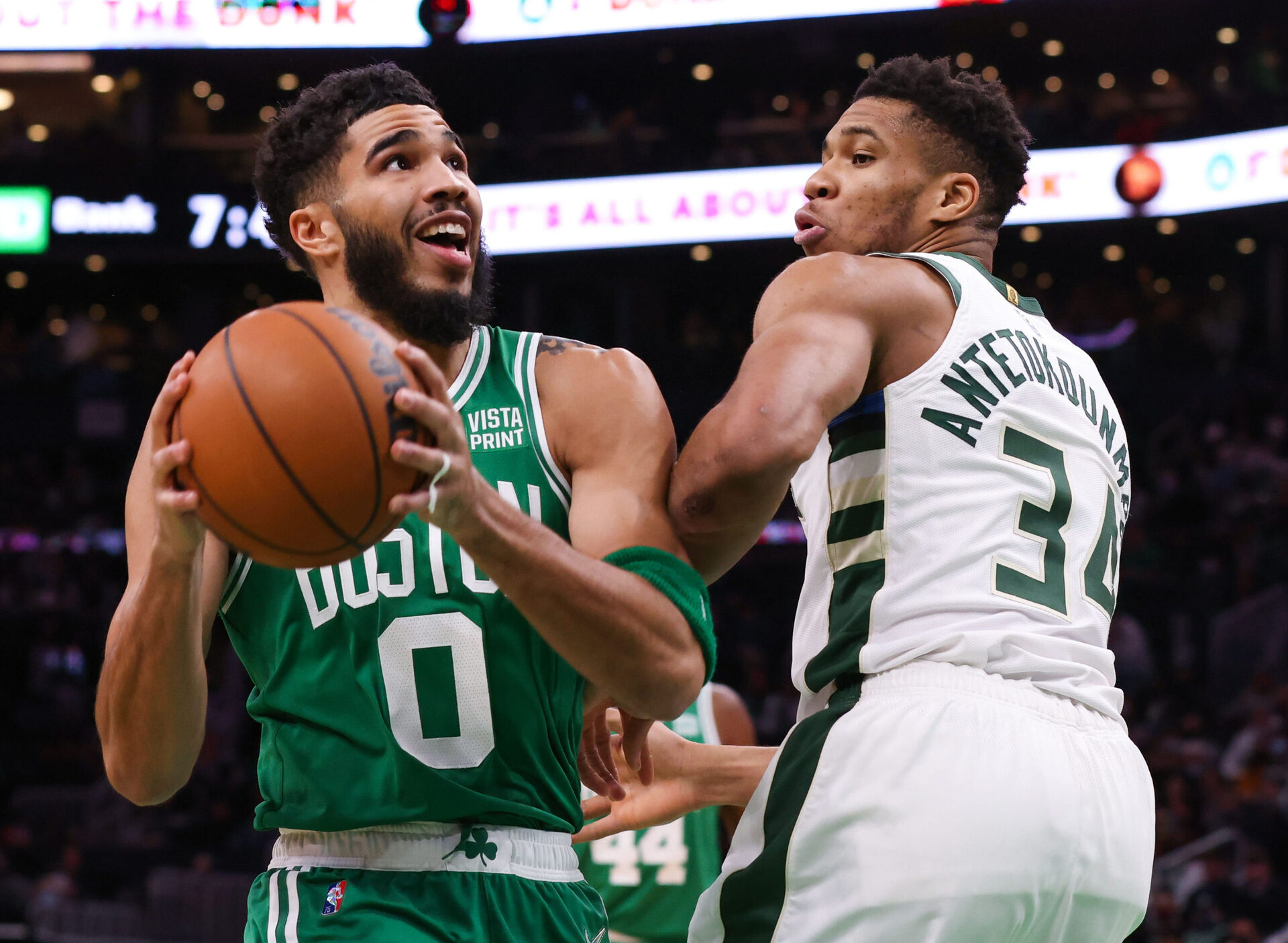 Boston Celtics forward Jayson Tatum (left) controls the basketball with both hands and looks to take a shot while Milwaukee Bucks forward Giannis Antetokounmpo (right) plays tight defense