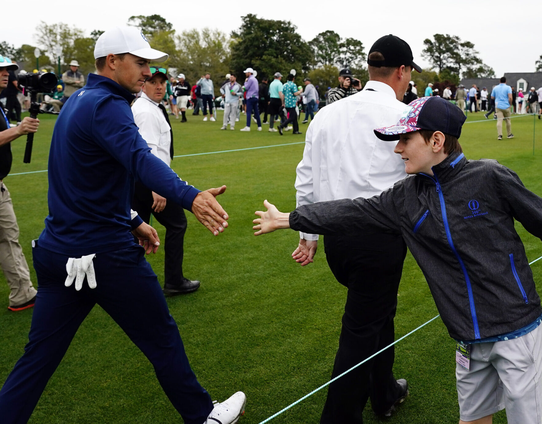 Max MacDonald of Brisbane, Australia, gets a high five from Jordan Spieth as he leaves the course during a practice round of The Masters golf tournament at Augusta National Golf Club on April 5, 2022.