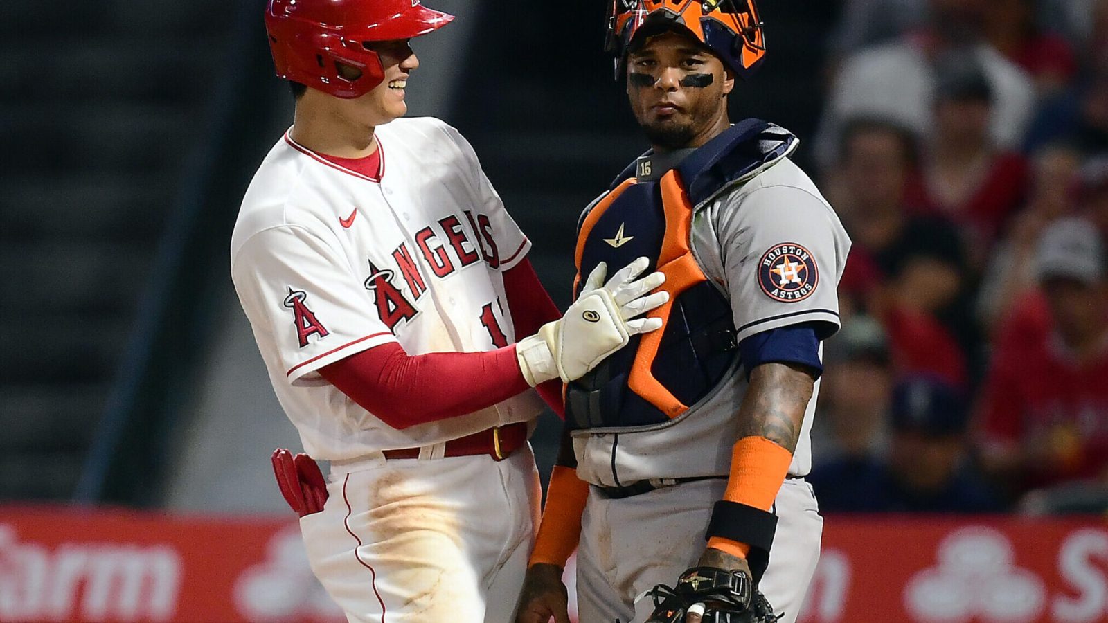 Los Angeles Angels designated hitter Shohei Ohtani (left) smiles and pats Houston Astros catcher Martin Maldonado (right) on his chest protector after a scoring a run
