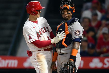 Los Angeles Angels designated hitter Shohei Ohtani (left) smiles and pats Houston Astros catcher Martin Maldonado (right) on his chest protector after a scoring a run