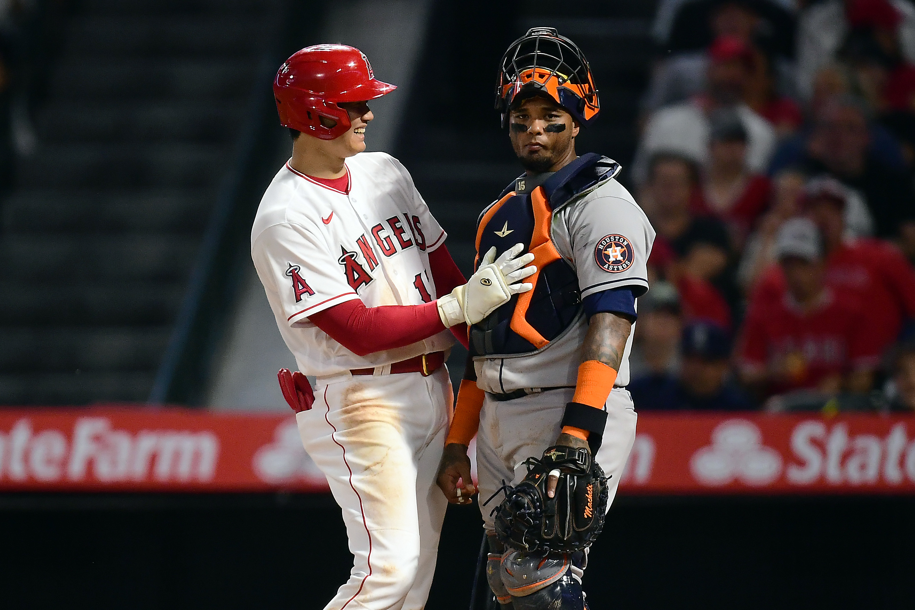 Los Angeles Angels designated hitter Shohei Ohtani (left) smiles and pats Houston Astros catcher Martin Maldonado (right) on his chest protector after a scoring a run