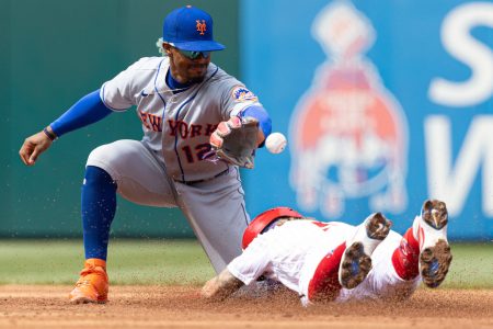 Philadelphia Phillies shortstop Bryson Stott (right) dives head first into second base as New York Mets shortstop Francisco Lindor (left) prepares to catch the ball with is left hand and tag out Stott, who attempted to stretch a single into a double