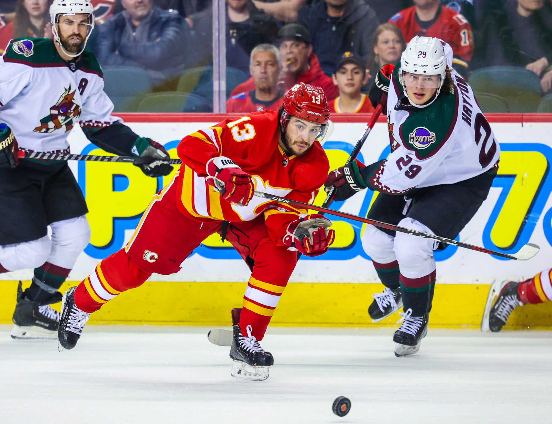 Calgary Flames' Johnny Gaudreau, center, skates past the Arizona Coyotes' Barrett Hayton, right, during the first period at Scotiabank Saddledome in Calgary on Saturday, April 16.