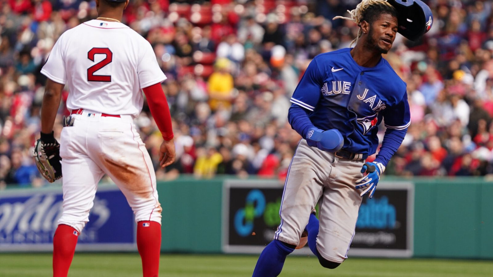 Toronto Blue Jays left fielder Raimel Tapia (right) runs to third base as Boston Red Sox shortstop Xander Boegarts (left, back turned) awaits a relay throw from the outfield