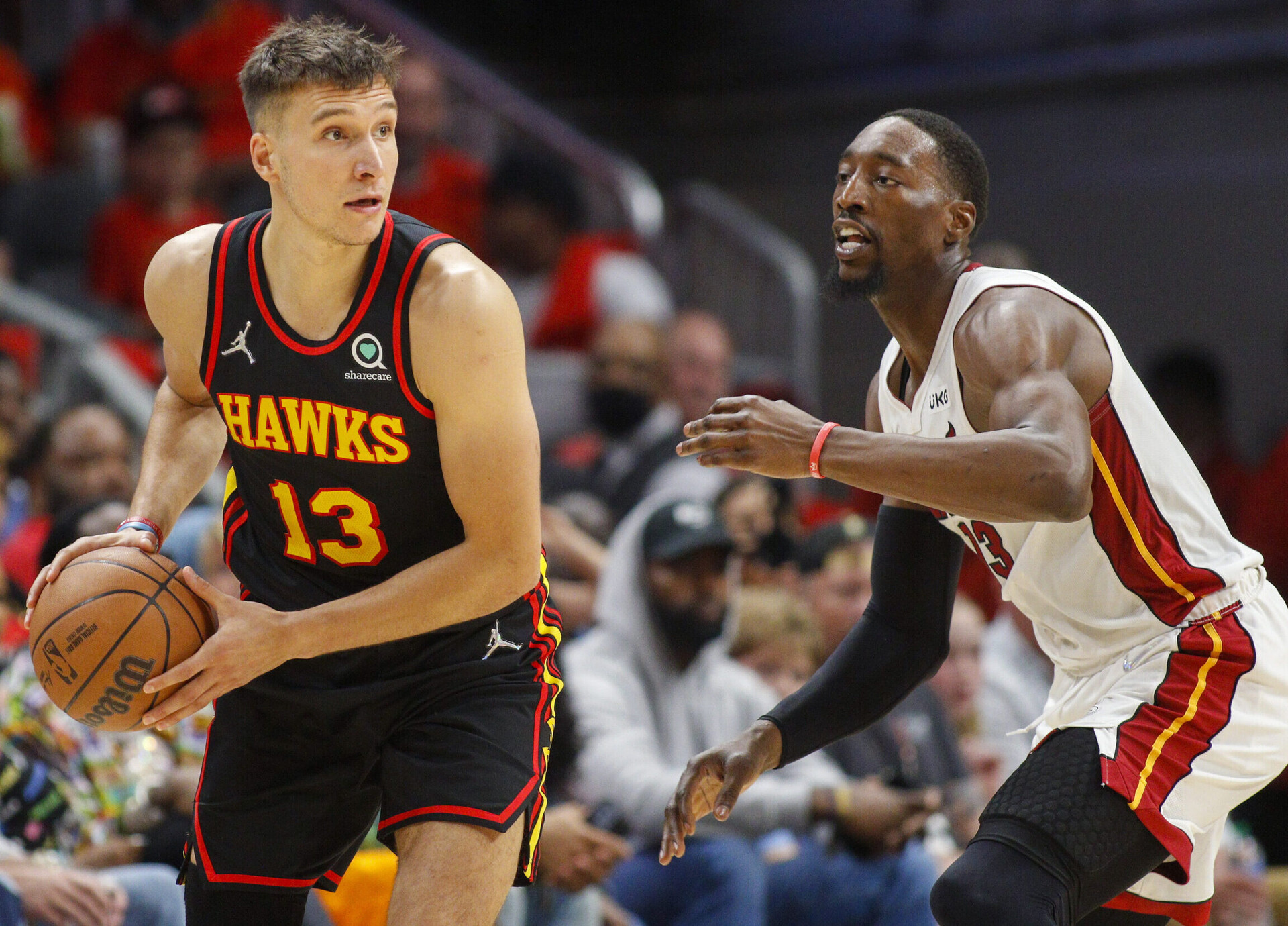 Atlanta Hawks guard Bogdan Bogdanovic (left) clutches the basketball with both hands while being defended by Miami Heat center Bam Adebayo (right) during game four of the first round for the 2022 NBA playoffs