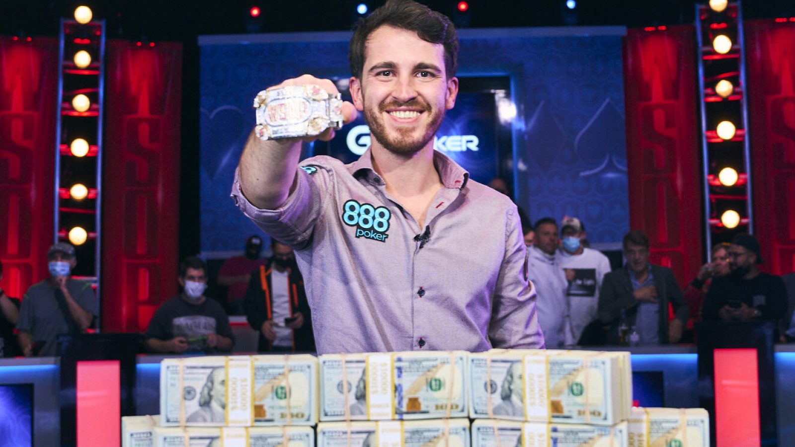 Koray Aldemir smiles in front of a large pile of money with a trophy bracelet on his right hand after winning the World Series of Poker Main Event on Nov. 17, 2021, at the Rio in Las Vegas.