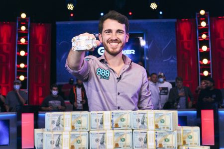 Koray Aldemir smiles in front of a large pile of money with a trophy bracelet on his right hand after winning the World Series of Poker Main Event on Nov. 17, 2021, at the Rio in Las Vegas.