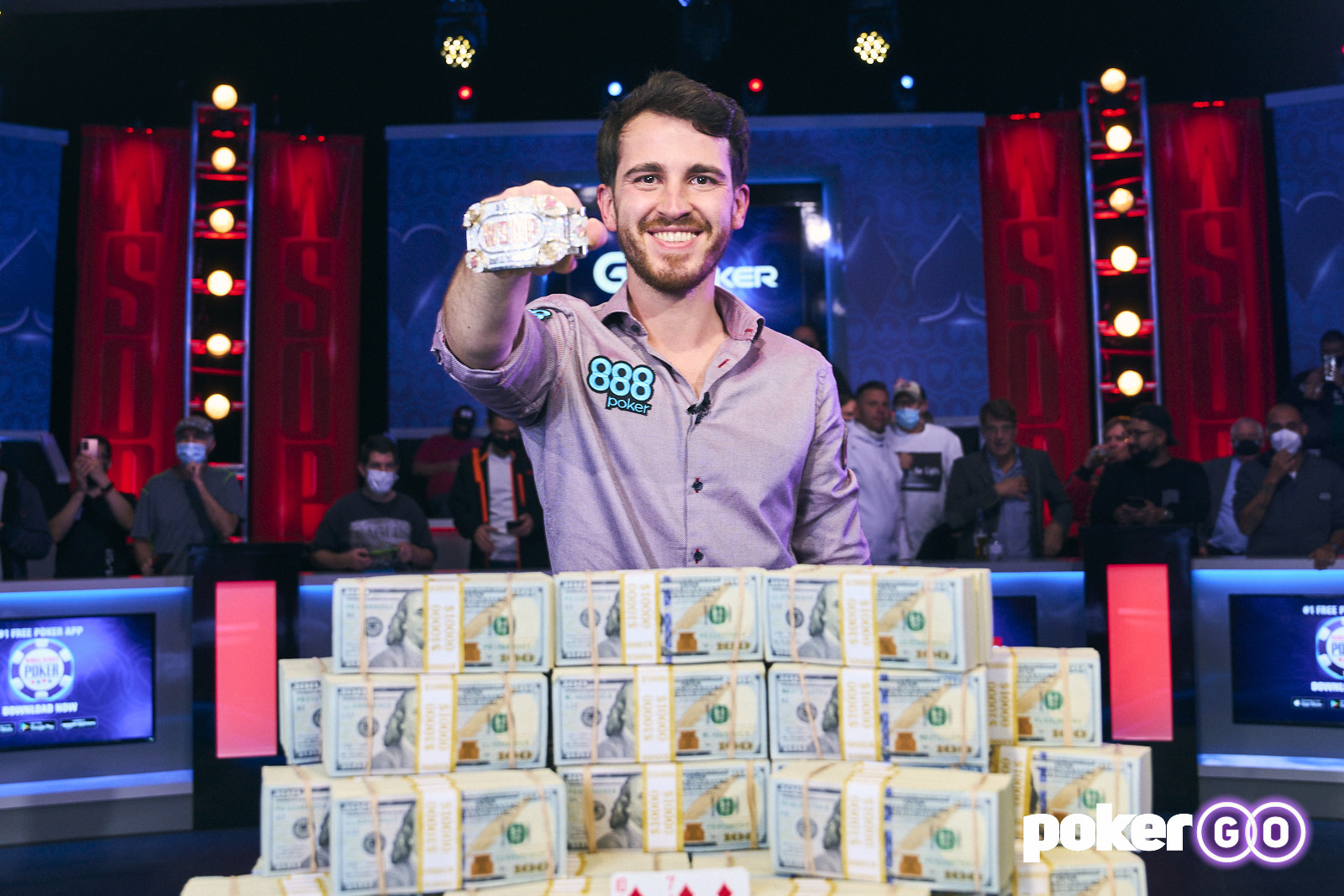 Koray Aldemir smiles in front of a large pile of money with a trophy bracelet on his right hand after winning the World Series of Poker Main Event on Nov. 17, 2021, at the Rio in Las Vegas.