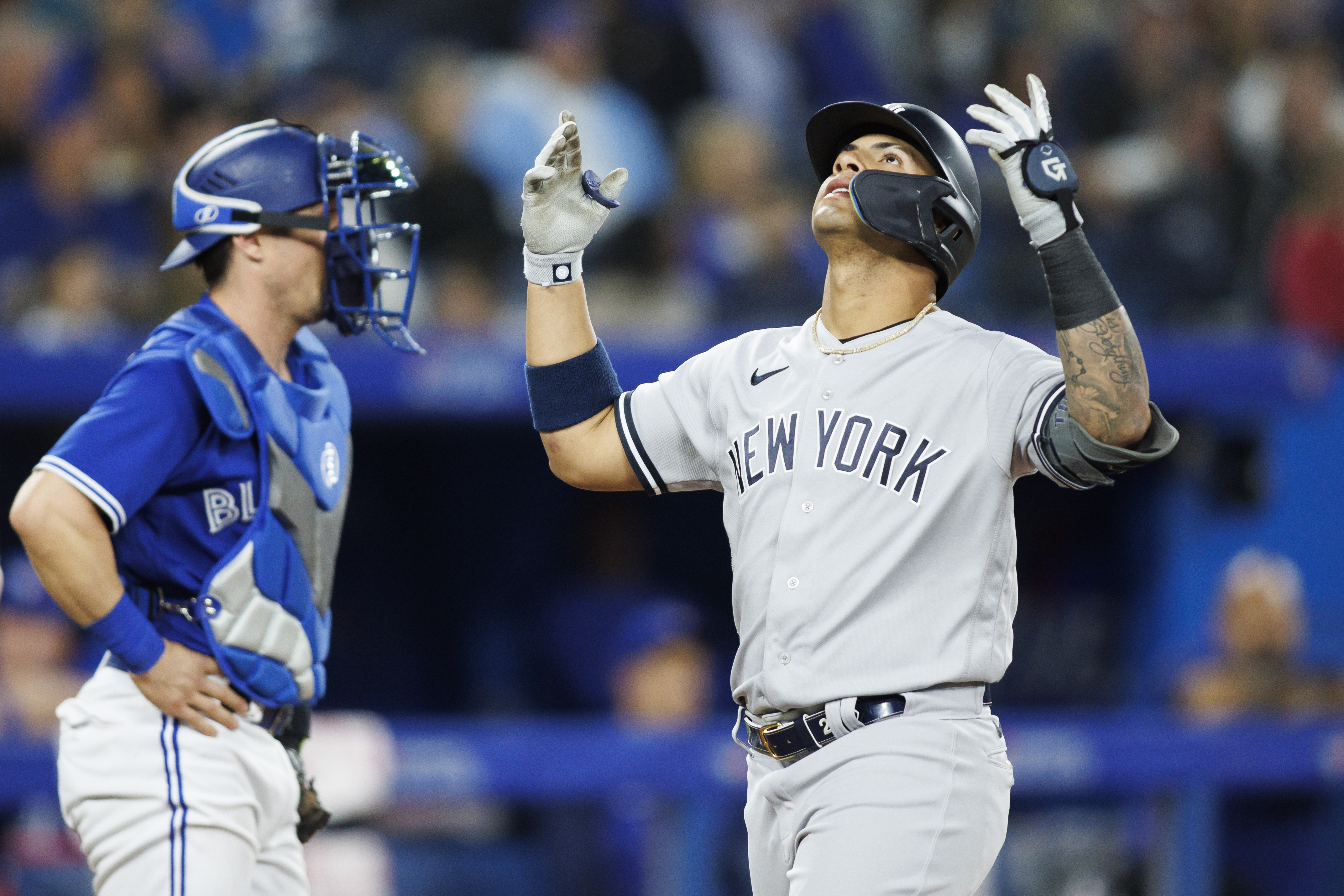 New York Yankees second baseman Gleyber Torres, right, puts his hands in the air and looks to the sky as he crosses home plate in front of Toronto Blue Jays catcher Tyler Heineman, left, after hitting a two-run home run on Monday, May 2, 2022, in Toronto.
