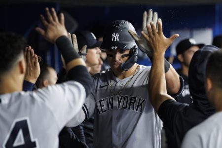 New York Yankees outfielder Aaron Judge, center, accepts congratulations from teammates in the dugout after hitting a home run against the Toronto Blue Jays on Tuesday, May 3, 2022, in Toronto.
