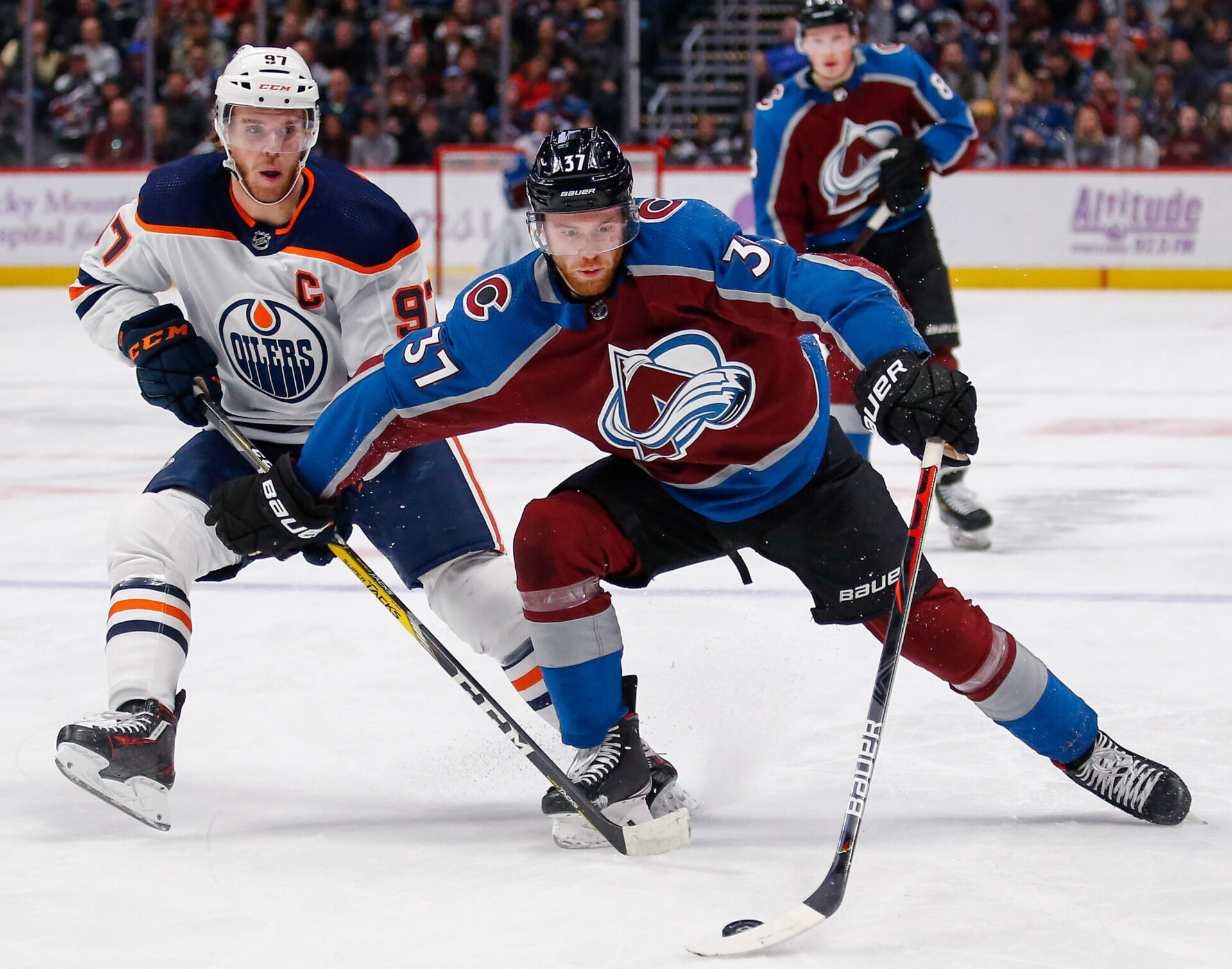 Colorado Avalanche left wing J.T. Compher (right) controls the puck under pressure from Edmonton Oilers center Connor McDavid (left)