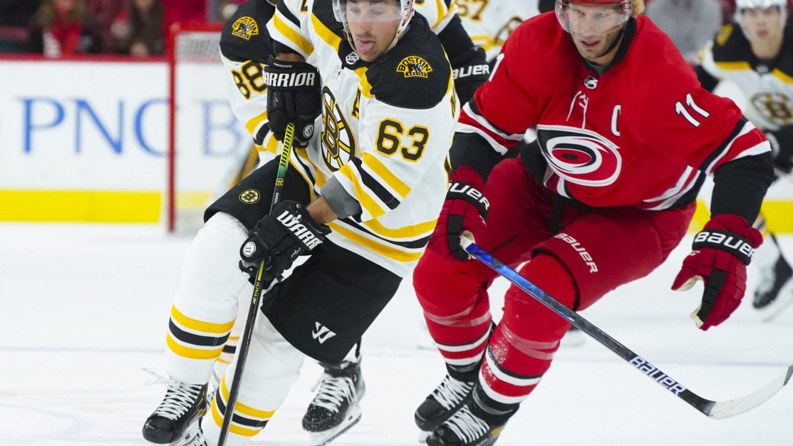 Boston Bruins center Brad Marchand (right) skates with the puck past Carolina Hurricanes center Jordan Staal (left)