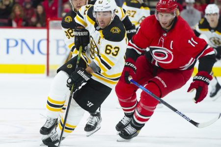 Boston Bruins center Brad Marchand (right) skates with the puck past Carolina Hurricanes center Jordan Staal (left)