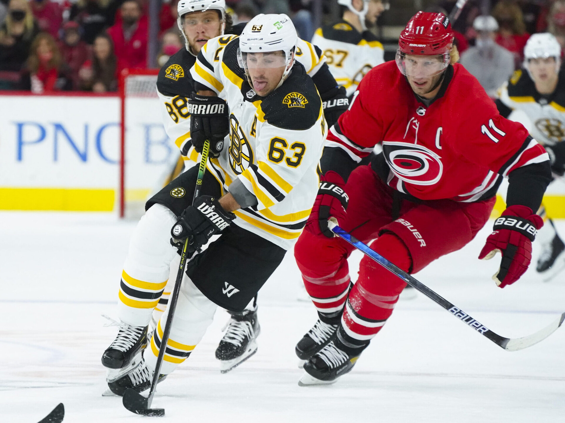 Boston Bruins center Brad Marchand (right) skates with the puck past Carolina Hurricanes center Jordan Staal (left)