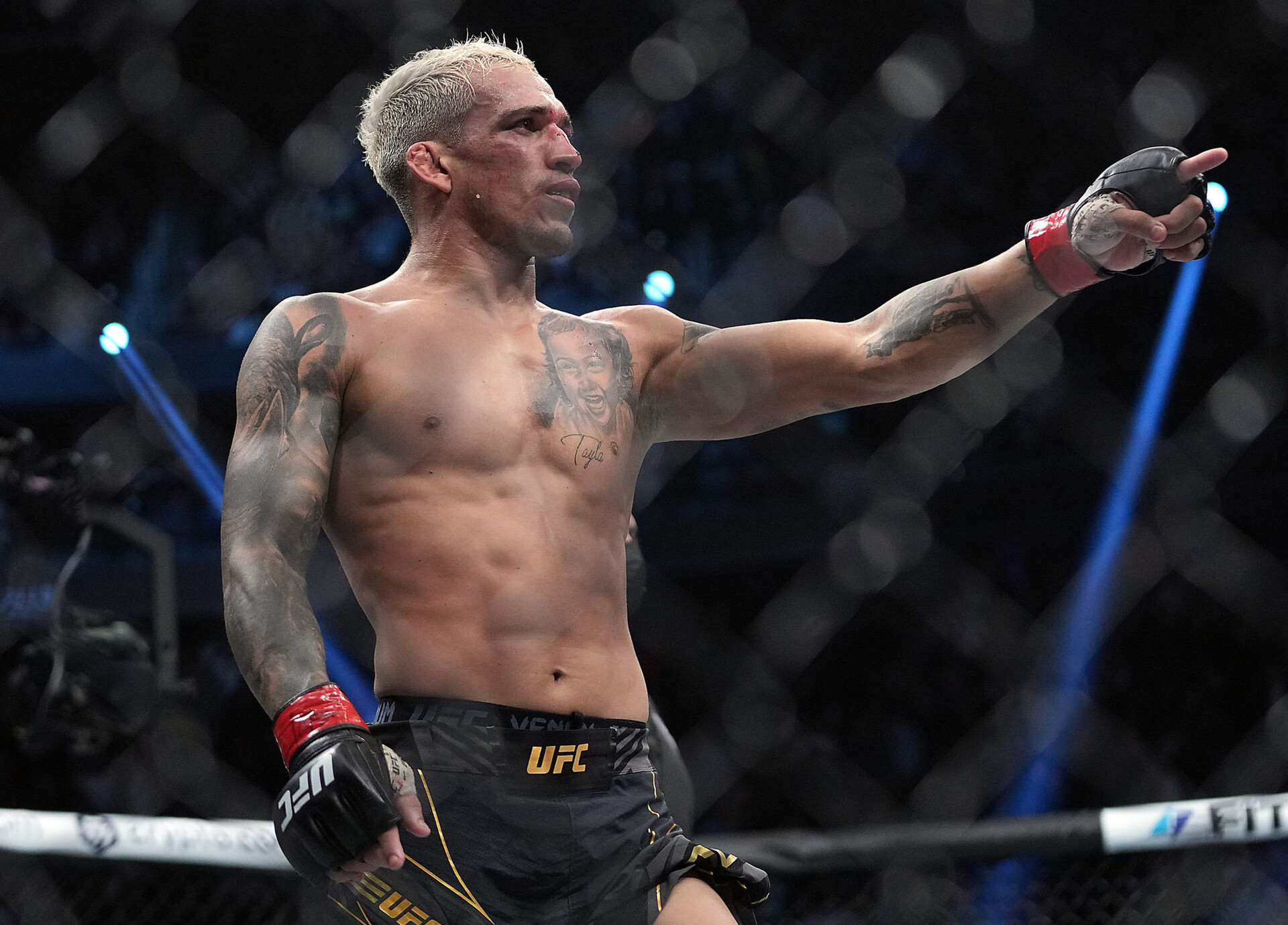 Charles Oliveira points to the crowd with his left hand as he celebrates his victory by submission against Dustin Poirier during UFC 269