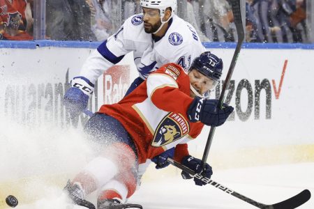 Florida Panthers center Sam Reinhart (right) loses his footing and is about to fall to the ice while trying to keep and Tampa Bay Lightning left wing Pierre-Edouard Bellemare (left) away from the puck along the boards