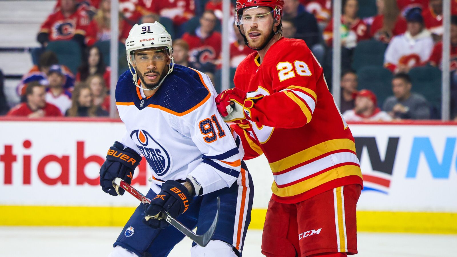 Edmonton Oilers left wing Evander Kane (left) and Calgary Flames center Elias Lindholm (right) fight for position while eyeing the puck