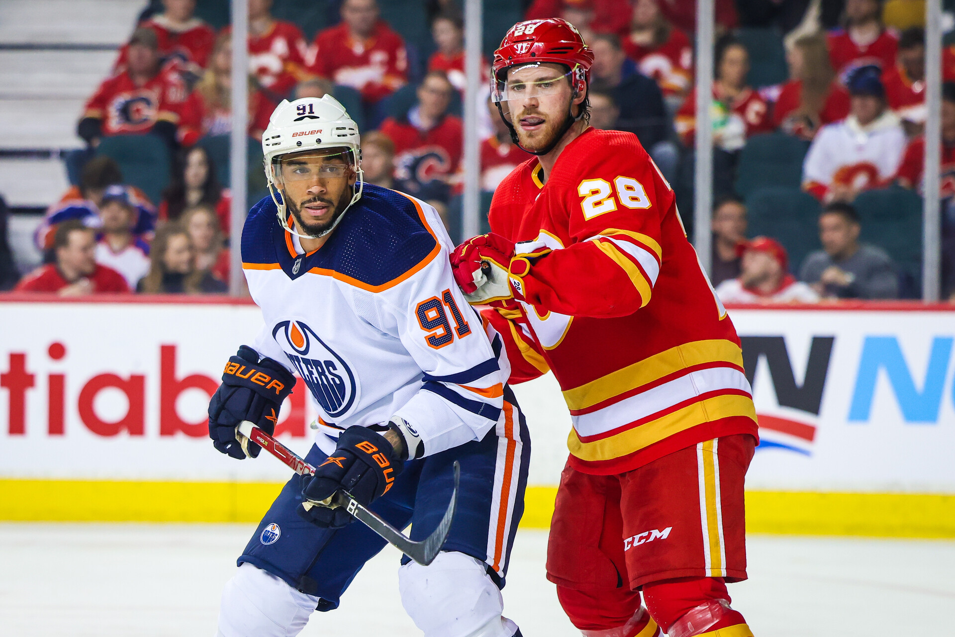 Edmonton Oilers left wing Evander Kane (left) and Calgary Flames center Elias Lindholm (right) fight for position while eyeing the puck