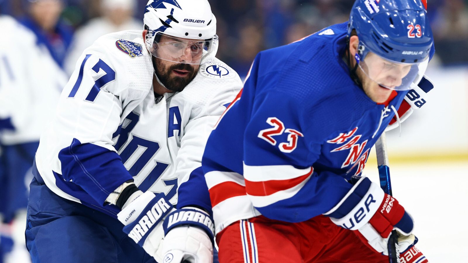 Tampa Bay Lightning left wing Alex Killorn (left) defends from behind as New York Rangers defenseman Adam Fox (right) tries to control the puck (unseen)