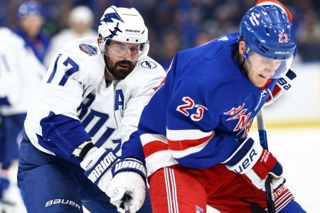 Tampa Bay Lightning left wing Alex Killorn (left) defends from behind as New York Rangers defenseman Adam Fox (right) tries to control the puck (unseen)