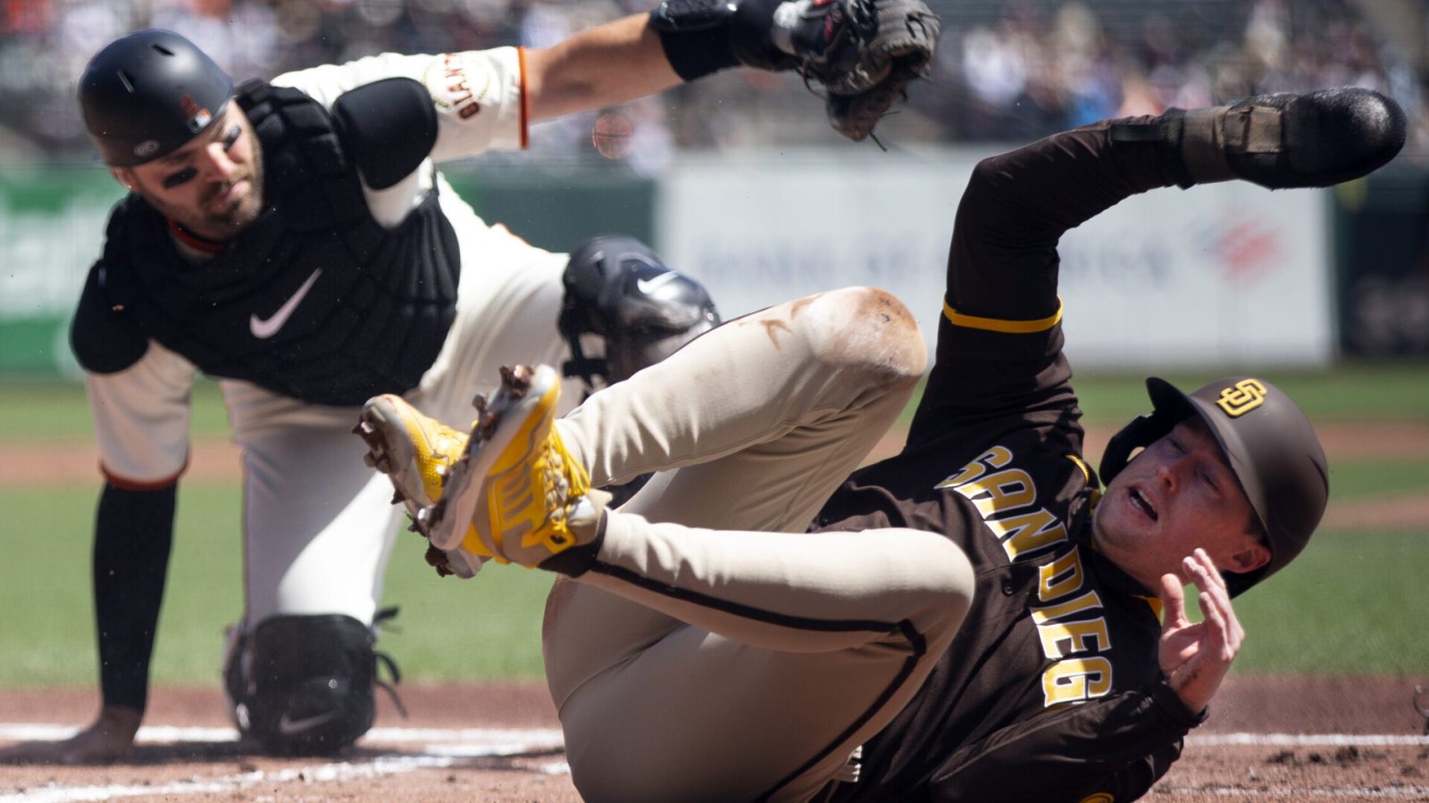 San Diego Padres second baseman Jake Cronenworth (right) rolls over on his back after being tagged out at home plate by San Francisco Giants catcher Curt Casali (left)