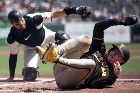 San Diego Padres second baseman Jake Cronenworth (right) rolls over on his back after being tagged out at home plate by San Francisco Giants catcher Curt Casali (left)