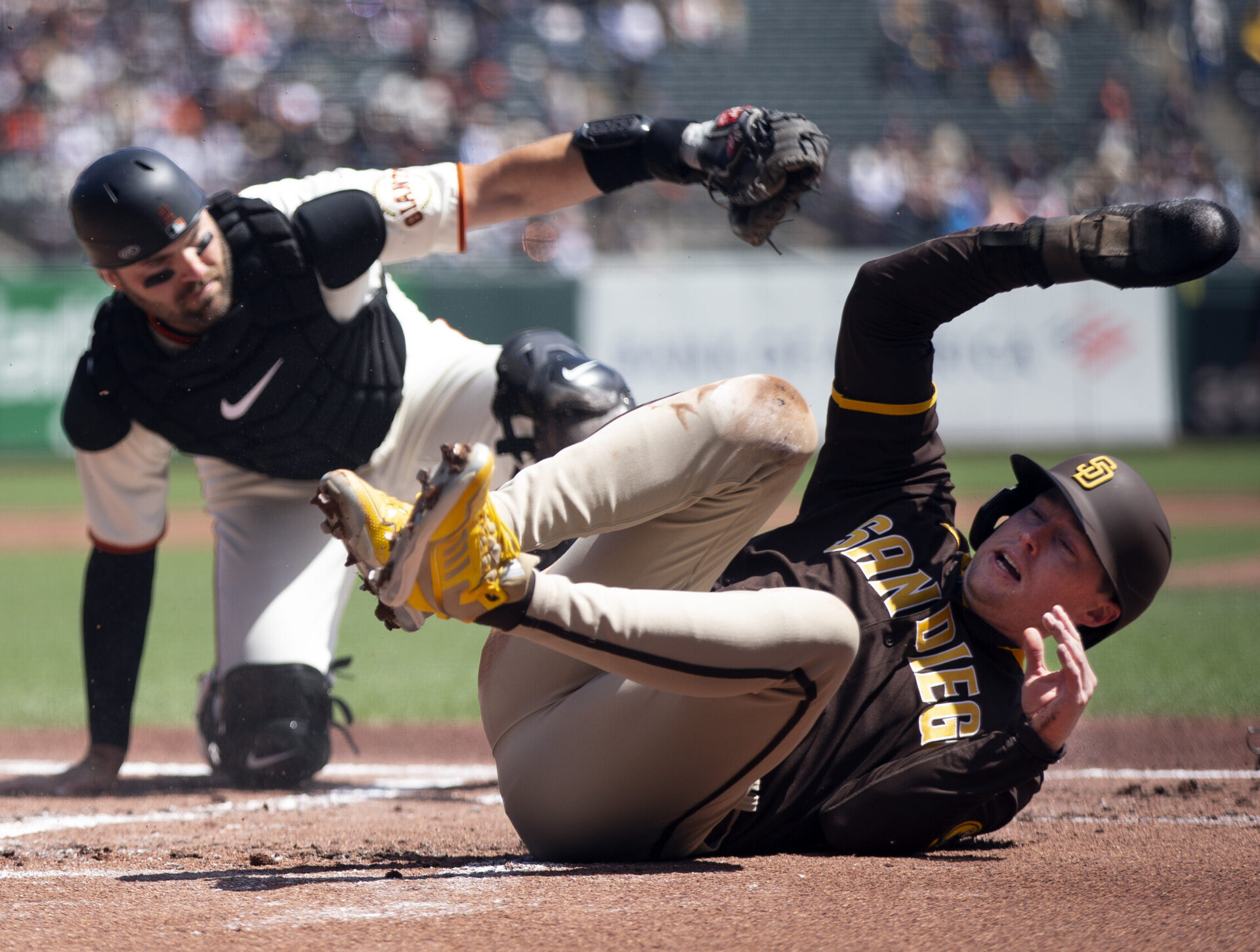 San Diego Padres second baseman Jake Cronenworth (right) rolls over on his back after being tagged out at home plate by San Francisco Giants catcher Curt Casali (left)
