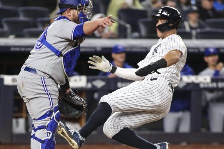 New York Yankees right fielder Aaron Judge (right) slides safely into a home plate as an unidentified Toronto Blue Jays catcher (left) directs his infield where to throw the ball