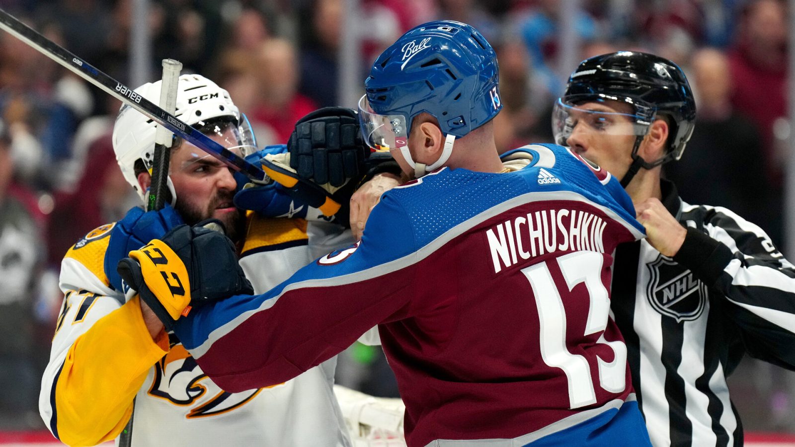NHL linesman Bryan Pancich (far right) breaks up a fight between Nashville Predators defenseman Dante Fabbro (left) and Colorado Avalanche right wing Valeri Nichushkin (right) during a 2022 Stanley Cup Playoff game