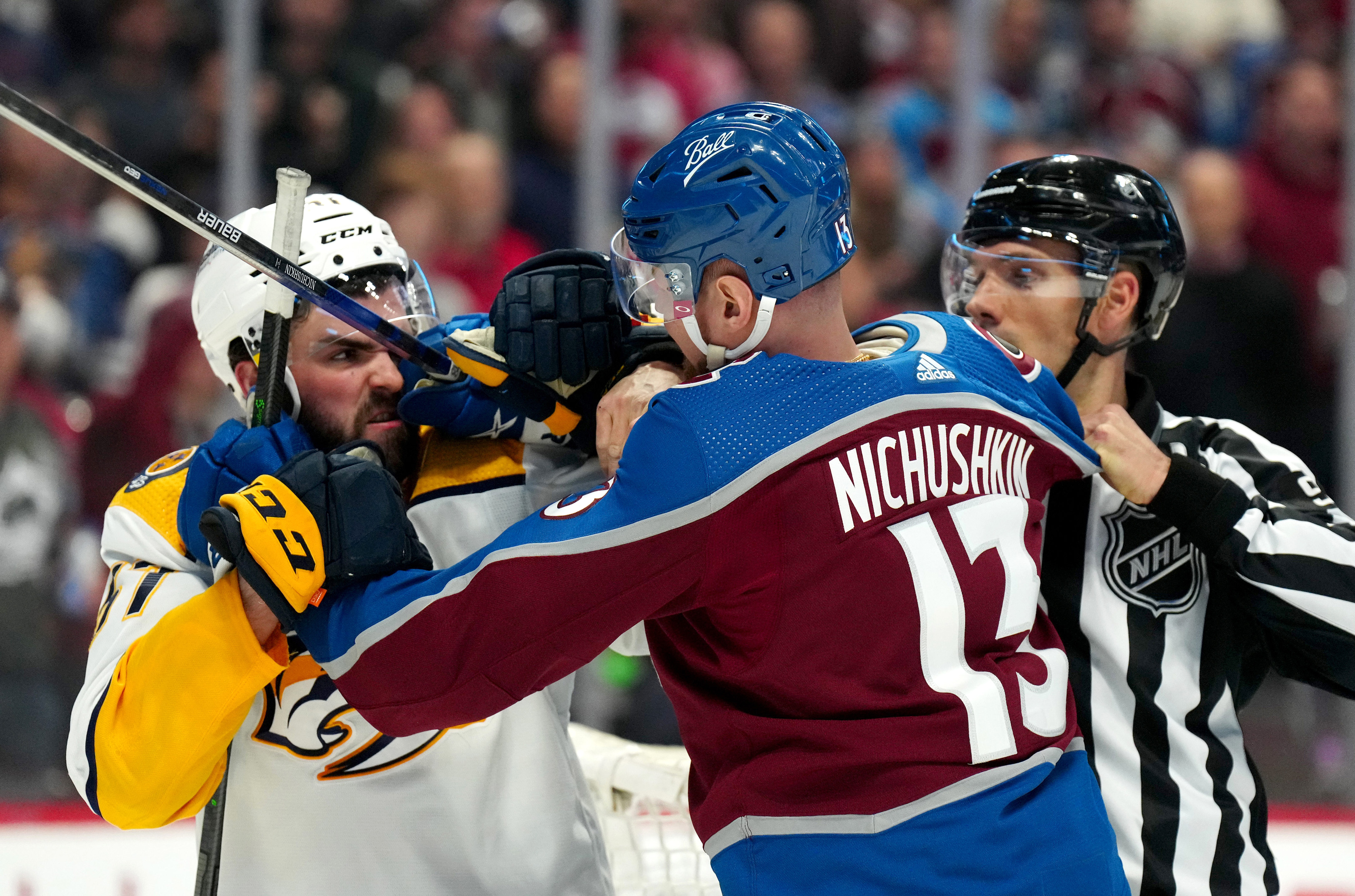 NHL linesman Bryan Pancich (far right) breaks up a fight between Nashville Predators defenseman Dante Fabbro (left) and Colorado Avalanche right wing Valeri Nichushkin (right) during a 2022 Stanley Cup Playoff game