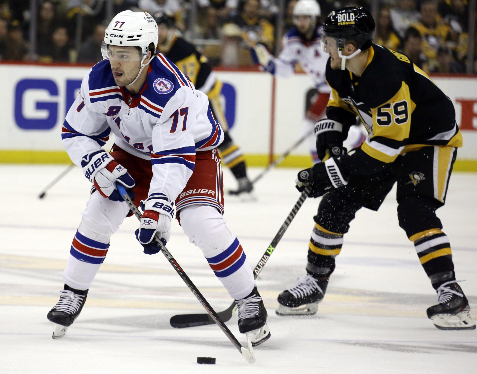 New York Rangers center Frank Vatrano (left) moves the puck ahead of Pittsburgh Penguins left wing Jake Guentzel (right) during a 2022 Stanley Cup Playoffs game