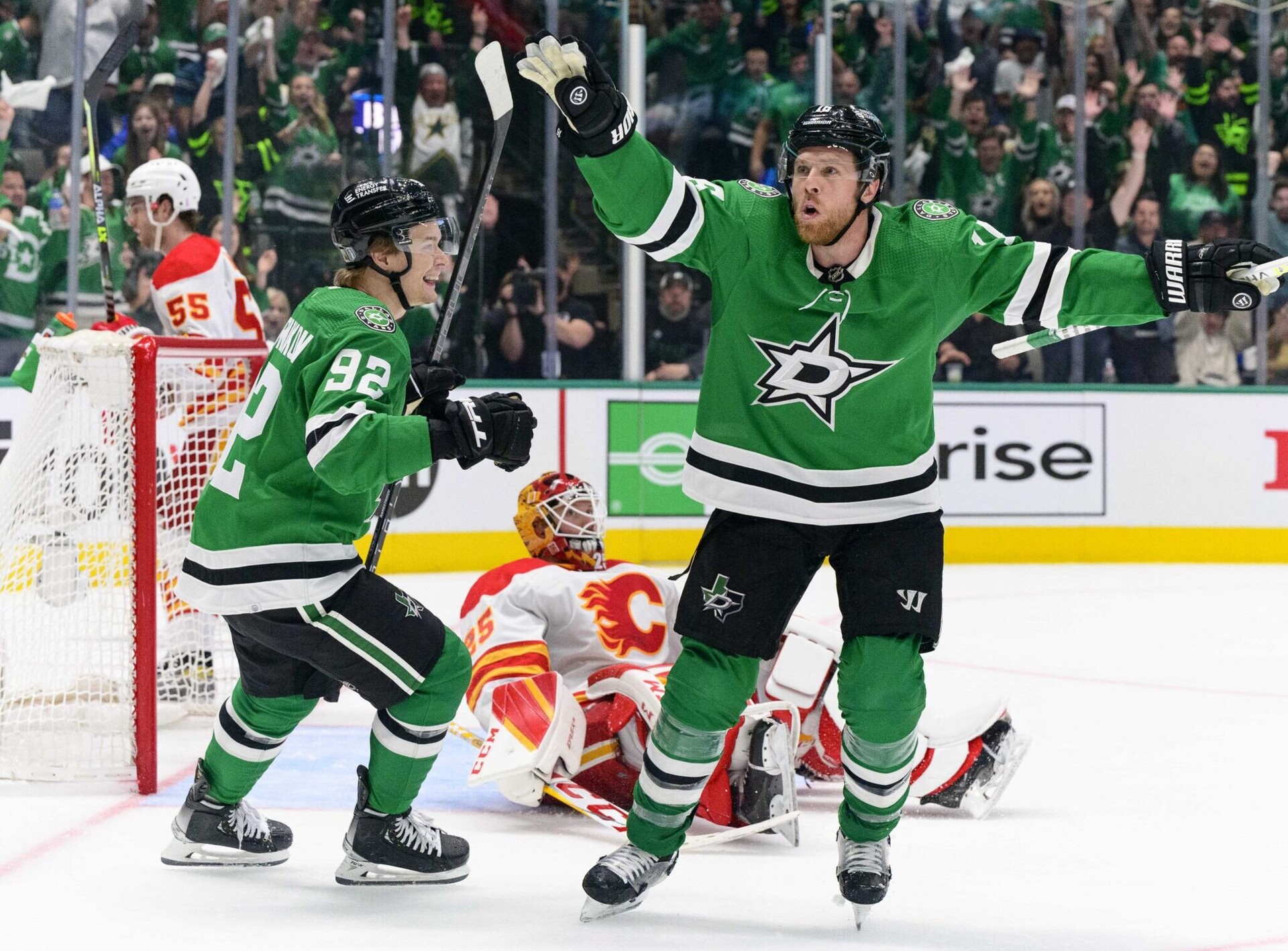 Dallas Stars center Vladislav Namestnikov (left) and center Joe Pavelski (right) celebrate Pavelski's against Calgary Flames goaltender Jacob Markstrom (rear) during a 2022 Stanley Cup Playoffs game