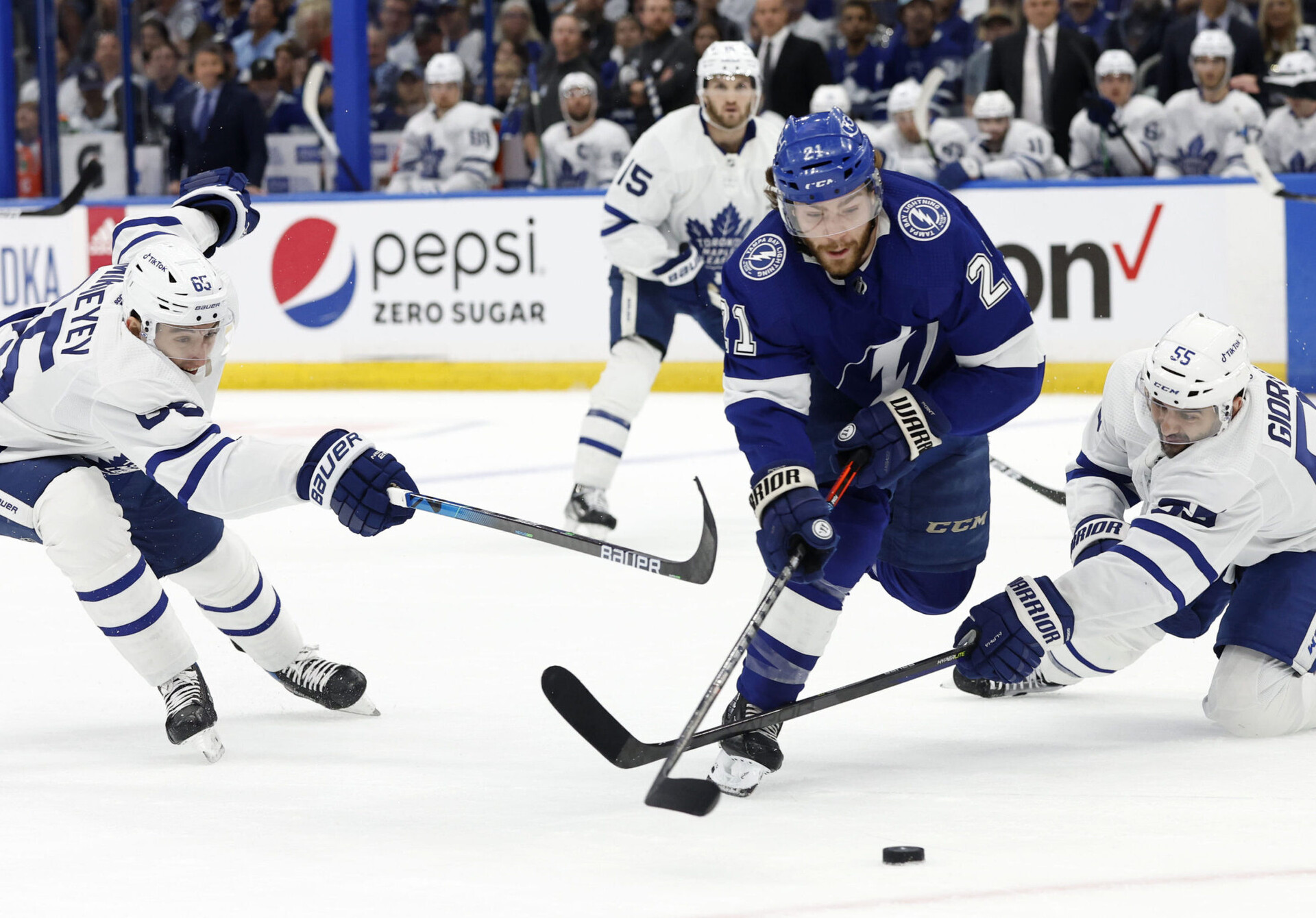 Tampa Bay Lightning center Brayden Point (center) skates with the puck as Toronto Maple Leafs right wing Ilya Mikheyev (left) and defenseman Mark Giordano (right) reach out with their sticks to try to slow him down during a 2022 Stanley Cup Playoffs game