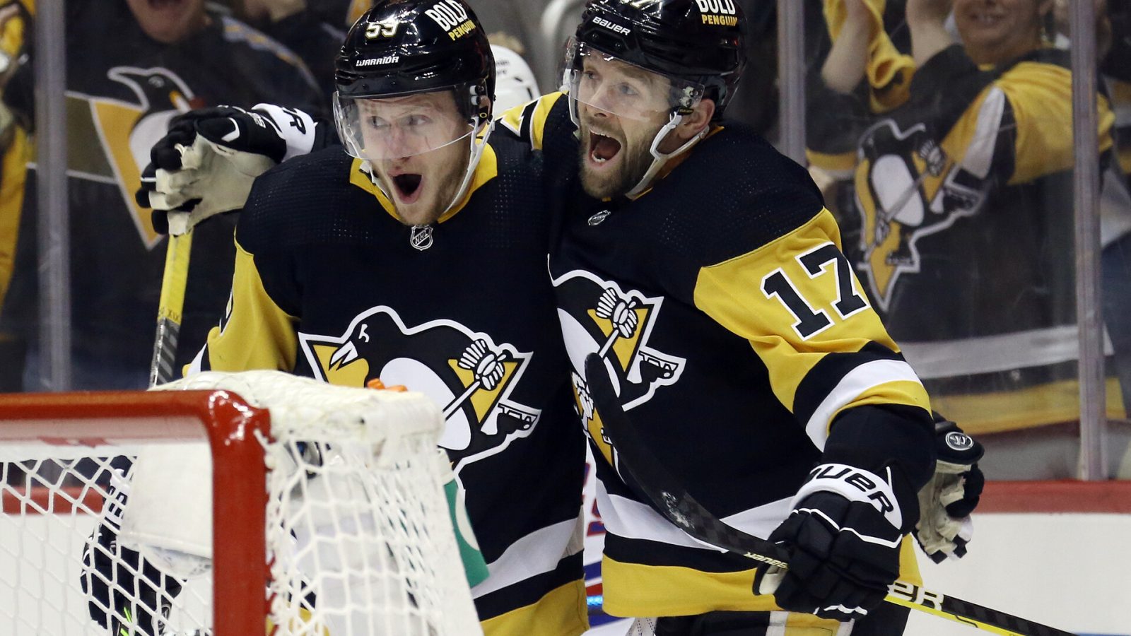 Pittsburgh Penguins left wing Jake Guentzel (left) and right wing Bryan Rust (right) celebrate a goal by Guentzel against the New York Rangers during a 2022 Stanley Cup Playoffs game