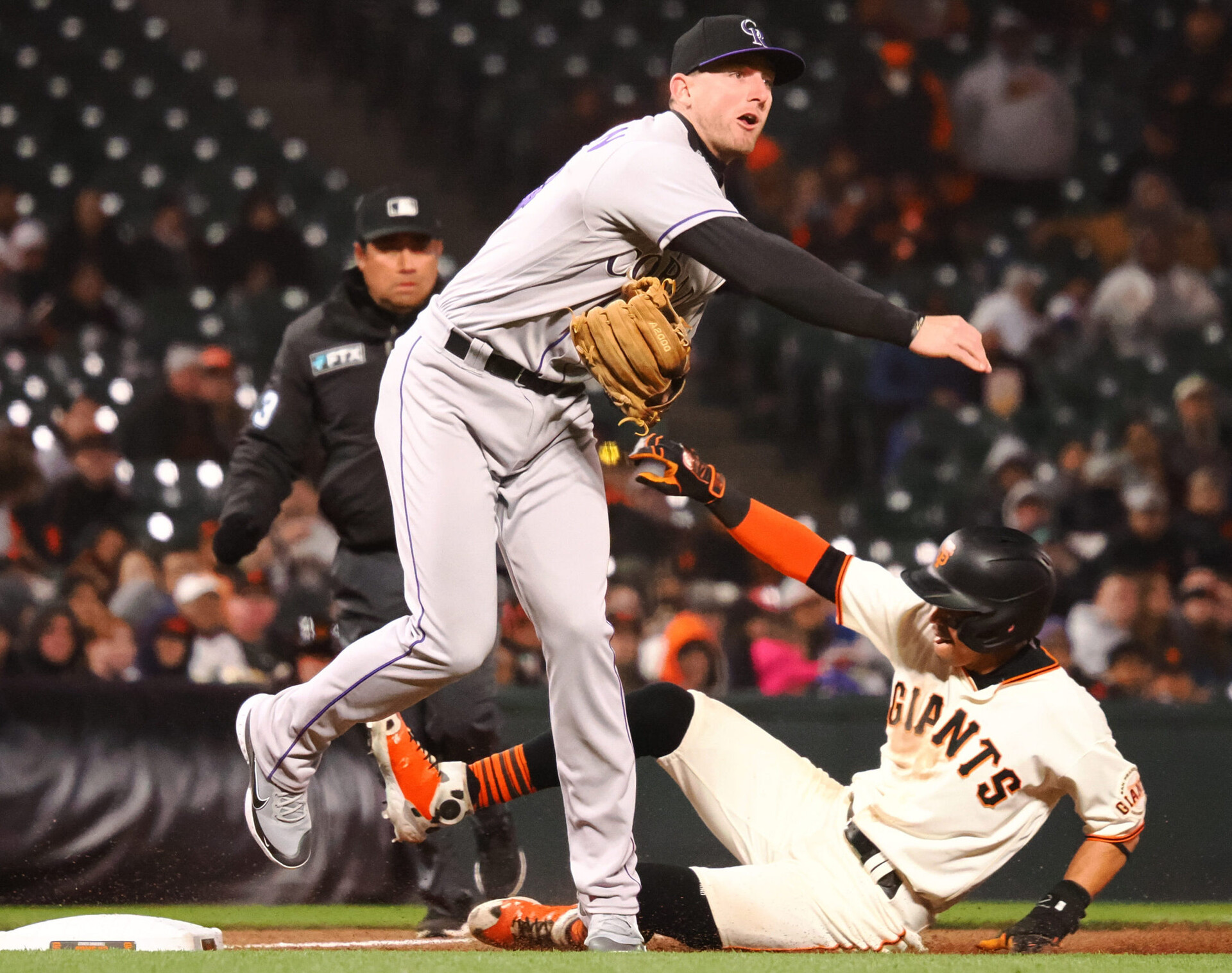 Colorado Rockies third baseman Ryan McMahon (right) follows through on a throw to second base to complete a double play as San Francisco Giants center fielder Mauricio Dubon (right) slides into third base