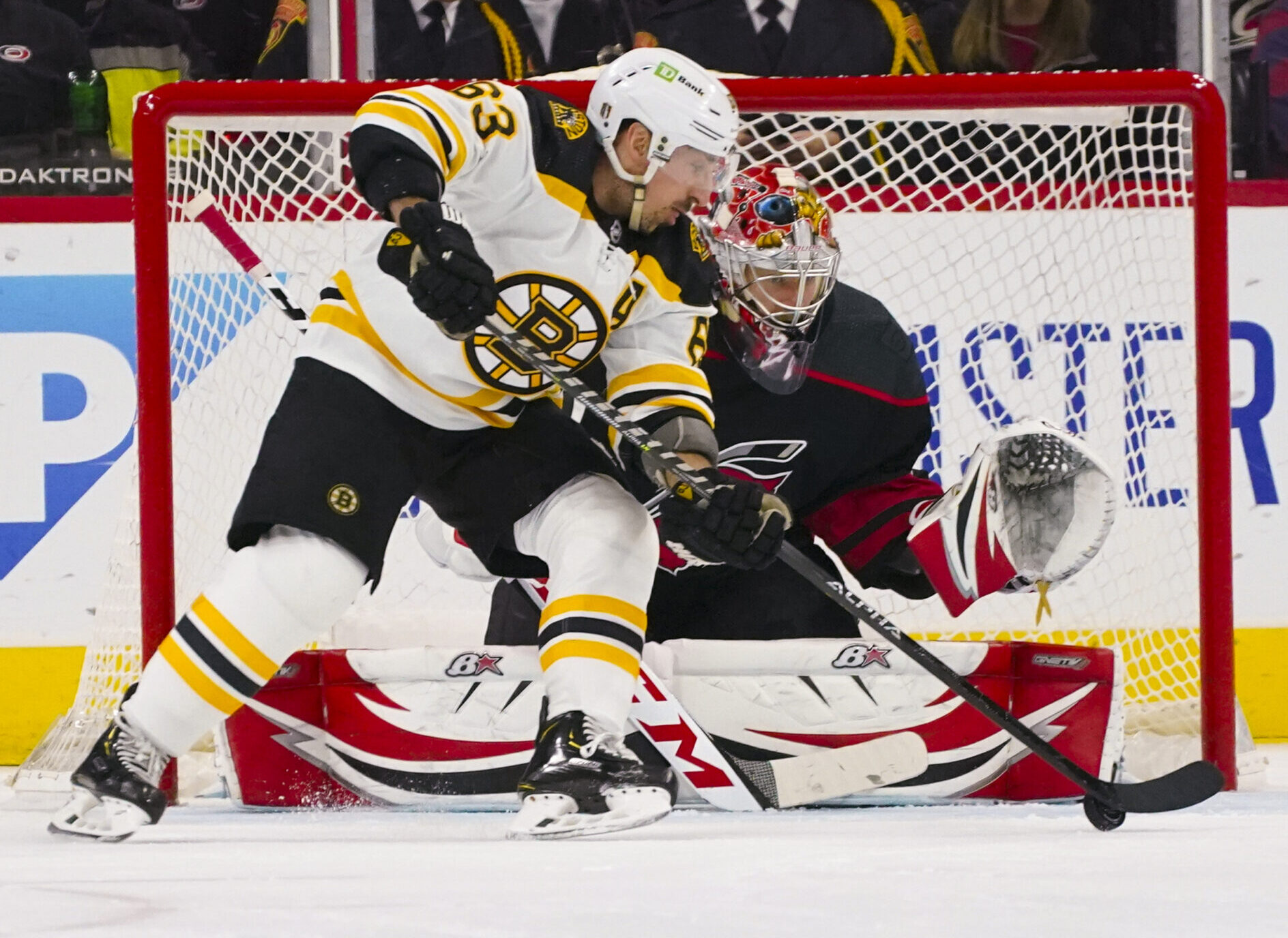 Boston Bruins left wing Brad Marchand (left) skates with the puck in front of Carolina Hurricanes goaltender Antti Raanta (right) during a 2022 Stanley Cup Playoffs game