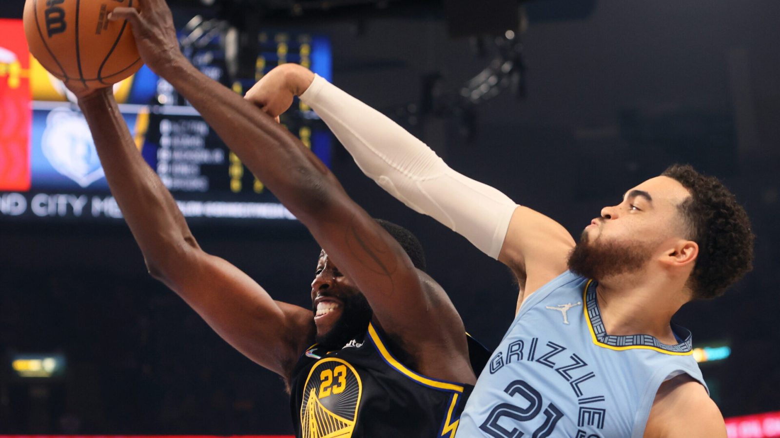 Golden State Warriors forward Draymond Green, left, grits his teeth as he grabs a rebound with both hands against Memphis Grizzlies guard Tyus Jones, right, on Wednesday, May 11, 2022, in Memphis, Tenn.