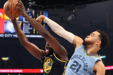 Golden State Warriors forward Draymond Green, left, grits his teeth as he grabs a rebound with both hands against Memphis Grizzlies guard Tyus Jones, right, on Wednesday, May 11, 2022, in Memphis, Tenn.