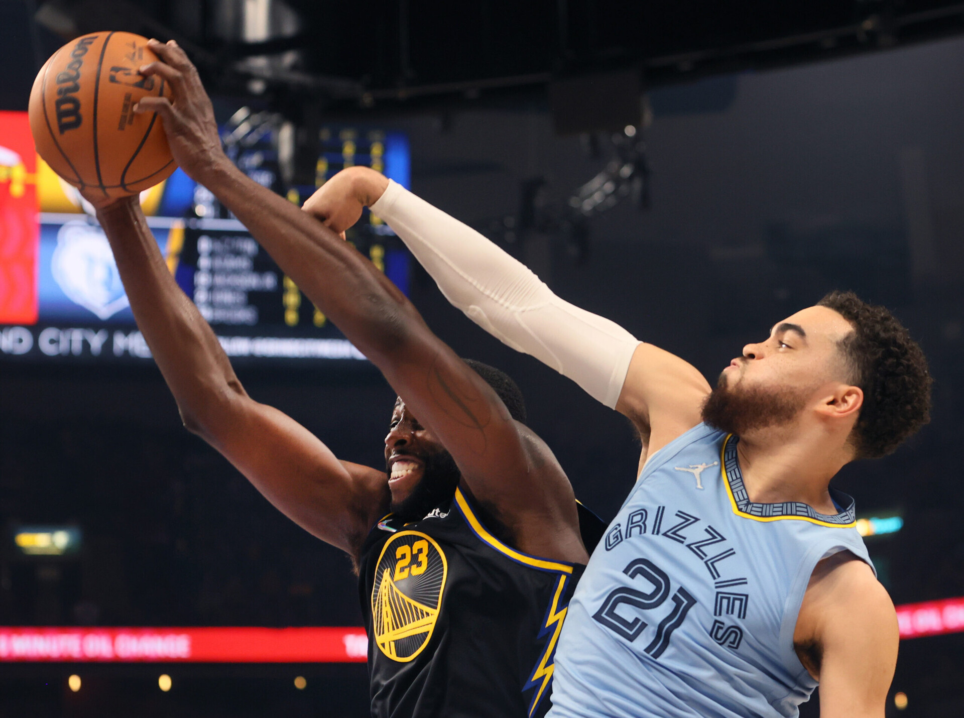 Golden State Warriors forward Draymond Green, left, grits his teeth as he grabs a rebound with both hands against Memphis Grizzlies guard Tyus Jones, right, on Wednesday, May 11, 2022, in Memphis, Tenn.
