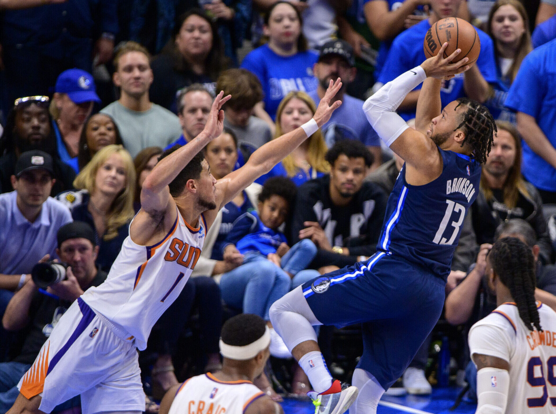 Dallas Mavericks guard Jalen Brunson, right, fades away to shoot over the outstretched left hand of Phoenix Suns guard Devin Booker, left, on May 12, 2022, in Dallas.
