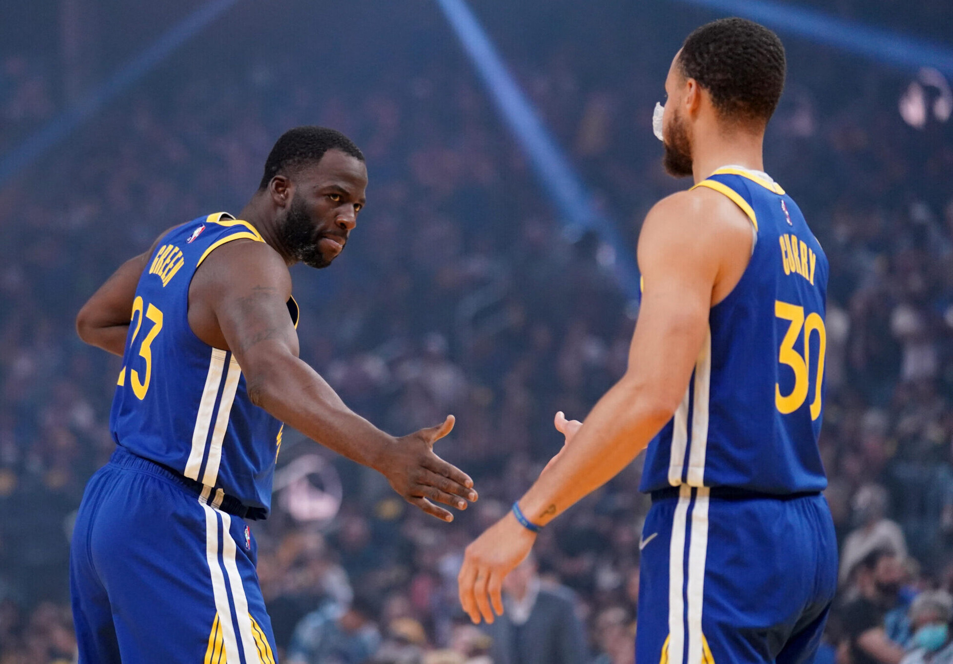 Golden State Warriors forward Draymond Green, left, extends his right hand to Warriors guard Stephen Curry, back to camera at right, on May 13, 2022, in San Francisco.